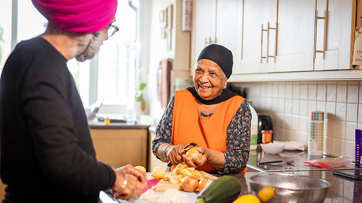 Man and woman stood in kitchen chopping vegetables together Man and woman stood in kitchen chopping vegetables together
