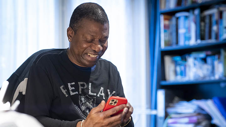 Looking at phone Joyful person looking at their smartphone in a room with bookshelves.